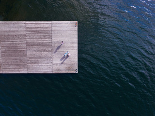 Aerial view from above of two girls singing at the old pier. One girl plays Ionica. Surrealism