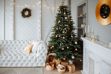 Christmas decor. Bright interior of the living room with large  elegant Christmas tree with toys and garlands  and white leather sofa