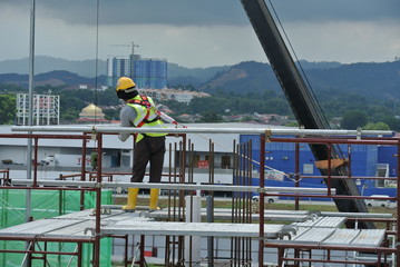 Wall Mural - Construction workers wearing safety harness and installing scaffolding at high level in the construction site. 