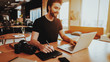 © VadimGuzhva - Smiling Graphic Designer Works on Laptop Indoors