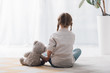 © LIGHTFIELD STUDIOS - rear view of little child sitting on floor with her teddy bear toy