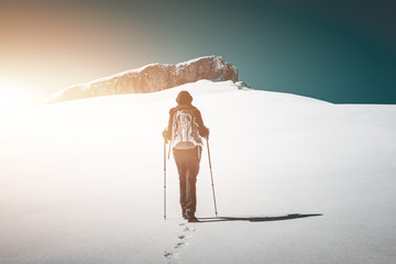 Wall Mural - Woman hiking across a snow field at dawn