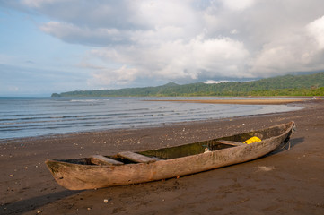 Wall Mural - Rustic fishing boat made from the trunk of a trees on a beach on the pacific coast of Colombia.