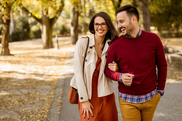 Wall Mural - Young woman and man walking in city park holding hands