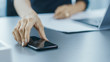 © Gorodenkoff - Shot of the Businesswoman Working at Her Office Desk and Reaching Out for Her Smartphone. Woman Picks up Mobile Phone from Her Desk. Focus on a Phone.