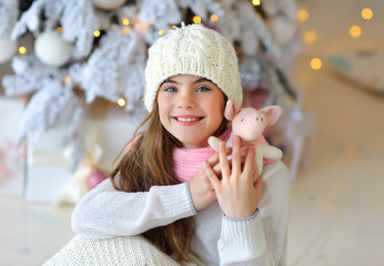 portrait of a beautiful 9-year-old girl in a knitted white hat in a New Year's interior