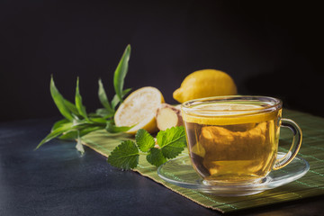 Cup with tea and mint, ginger on dark background. Chinese tea concept.