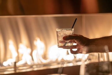 Wall Mural - Hand holding a glass of red whine against fire pit