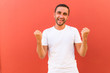 © F8  \ Suport Ukraine - Portrait of a happy young man in white t-shirt celebrating win isolated over red background