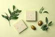 Handmade soap bars and leaves with olives on color background, top view