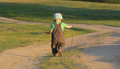 Kid walking away on a country road