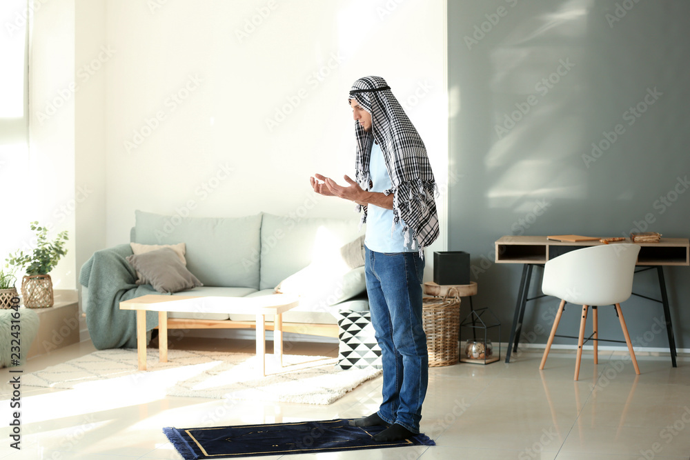 Young Muslim man praying at home