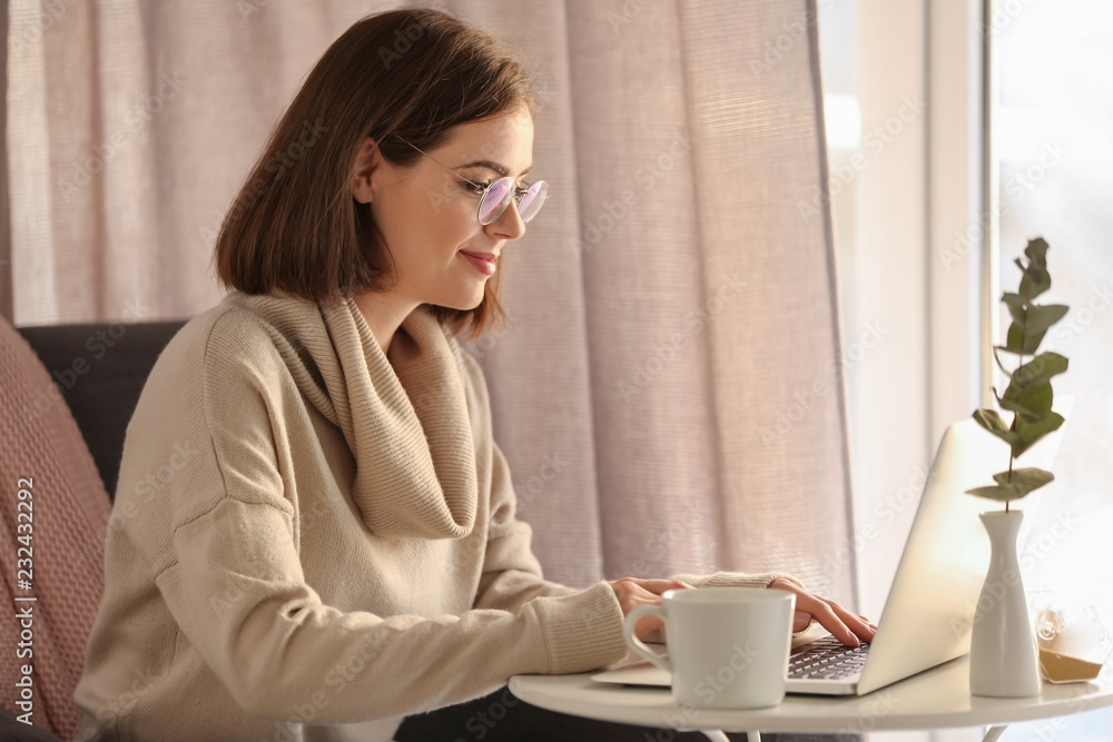 Beautiful young woman using laptop at home