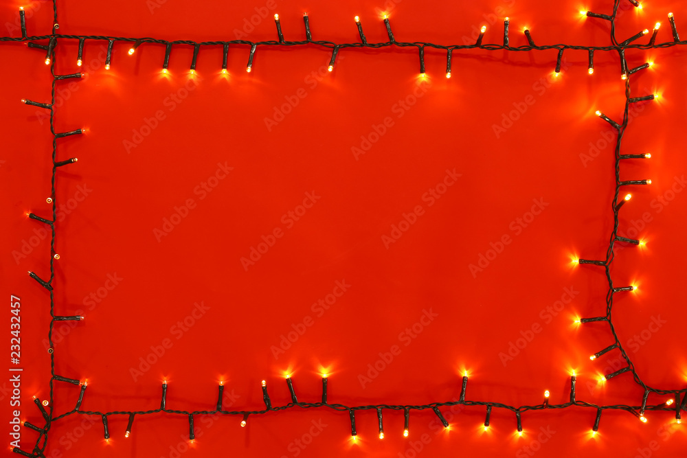 Christmas lights on red background, top view