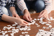 © Pixel-Shot - Young couple doing jigsaw puzzle at home, closeup