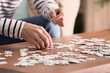 © Pixel-Shot - Young man doing jigsaw puzzle at home, closeup