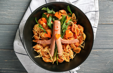 Plate with pasta and sausage for child on wooden table