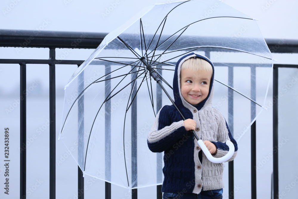 Cute little boy with transparent umbrella outdoors