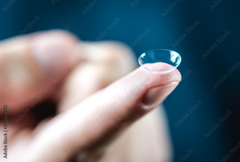 Contact lenses macro close up. Man holding lens on finger. Customer, patient or eye doctor, oculist or optician in clinic. Myopia, eye sight or optometry concept. - obrazy, fototapety, plakaty 
