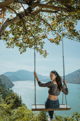 Wall Mural - woman portrait enjoying nature from a hill top sitting on a swin