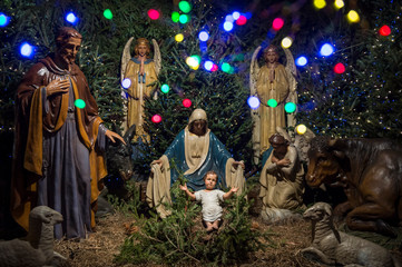 Christmas nativity scene with baby Jesus in the manger with wise men and angels and colorful holiday lights