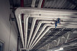 Metal pipes in thermal insulation winding on the ceiling of an industrial enterprise.