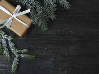 Christmas gift with white ribbon on black background with Christmas tree branches