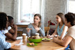 © fizkes - Diverse multi-ethnic students sitting around circle table listen schoolmate ideas studying together in cafe. Multiracial best friends gathered together doing exercise homework making notes on notepad