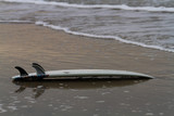 Fototapeta  - surfboard lying on the beach upside down near the shore line