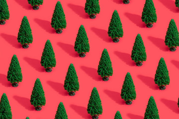 Minimal composition pattern background of green Christmas trees on pastel red. New Year concept.