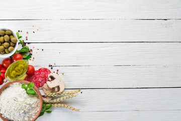 Ingredients for pizza. Mushrooms, sausages, tomatoes, vegetables. Top view. On a white wooden background. Free copy space.