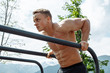 Strong crossfit sportsman with naked perfect torso doing dips on horisontal bars in outdoor sportfield in mountains area, warming-up set before lifting heavy weights. Active and Health Life Concept