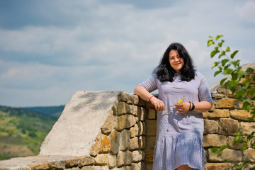 Wall Mural - Beautiful young girl with black hair posing against nature background.