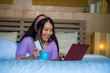 © TheVisualsYouNeed - young beautiful happy Asian Chinese woman using credit card internet banking on laptop computer at home in bed smiling shopping online e-commerce concept