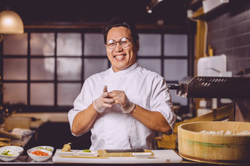 Wall Mural - cheerful positive guy in white uniform taking off gloves after preparing of sushi , close up photo.chef after finishig of cooking