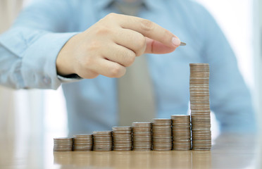 Businessman Sitting at Desk and Stacking Coins