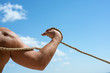 Gaining muscle. Sport training. Strong arm and shoulders tugging rope. Test of muscular strength. Physical strength and muscular power. Sport and fitness. Male muscular hand pulling rope
