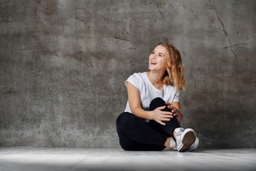 Wall Mural - beautiful smiling woman sitting on floor against concrete wall