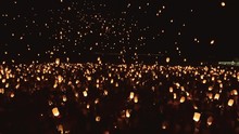 Drone Shot Of Thousands Of Glowing Lanterns Flying Across Screen. Beautiful Floating Lanterns Light The Night Sky As Thousands Of People Gather Throw Fire Lanterns In The Sky.