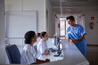 © Stocksy - Hospital staff talking in a relaxed moment at the desk of a patient room floor