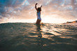 © Stocksy - Girl In Striped Swimsuit Jumping In The Waves