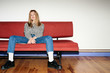 © Stocksy - Emotionless young woman on red sofa