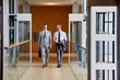© Stocksy - Male Colleagues Talking While Walking In Corridor