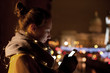 © Stocksy - Young woman using phone at night