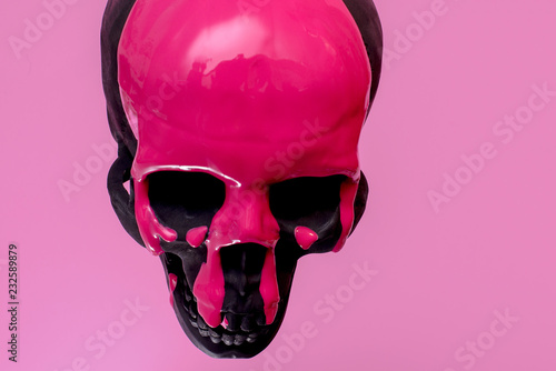 Black Skull With Pink Paint Running Down It Against A Pink