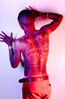 © Stocksy - Bare chested heavily tattooed mans torso under red, pink and blue lighting