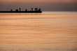 Silhouette of people fisherman on pier while beautiful sea sunset or dawn. Focus is foreground
