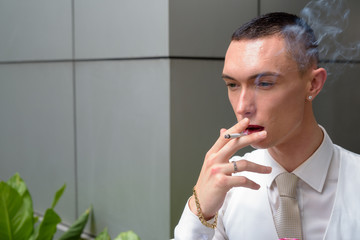 Young androgynous homosexual LGTB businessman smoking cigarette