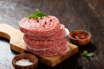 raw ground beef meat burger steak cutlets on dark wooden background.