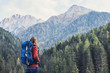 Young woman traveler in Alps mountains. Travel and active lifestyle concept. Traveler girl with backpack enjoying nature